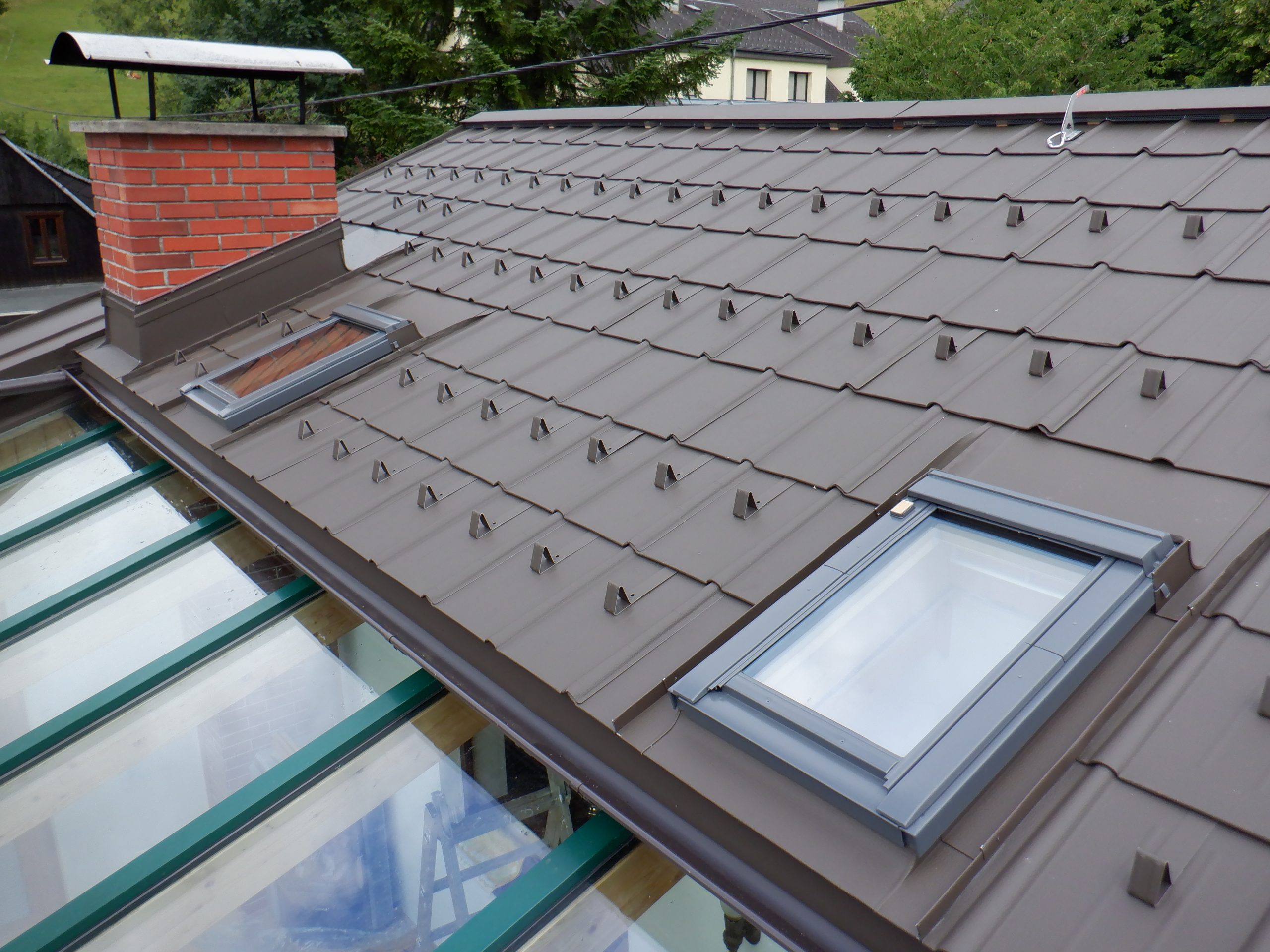 Prefa Dachplatten P10 Farbe Braun, Einbindung von Velux Dachflächenfenster sowie einer Kamineinfassung. Durchgehende Firstentlüftung.
